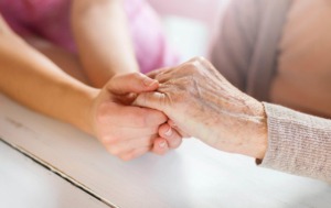 Seniorin hält die Hände mit der Betreuerin