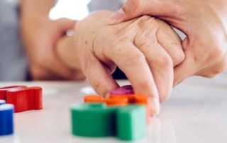 Pflegefachfrau hilft Seniorin beim Spielen