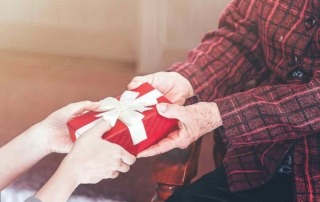 Seniorin übergibt Geschenk an Enkelin